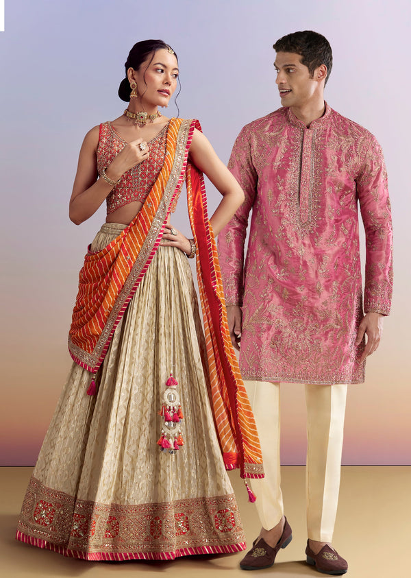 Festive Wedding Couple Set – Orange Brocade Bridesmaid Lehenga with Leheriya Dupatta for Her And Pink Embellished Tissue Kurta Set for Him