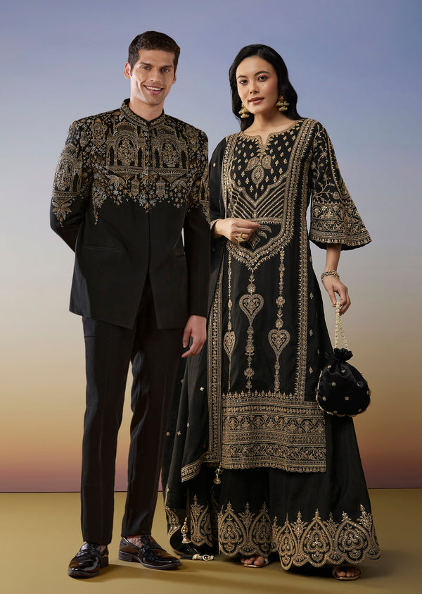 Bold Festive Couple Set – Black Silk Palazzo Suit With Zari Thread And Sequins Work For Her And Black Suiting Jodhpuri Pant Set With Embroidery For Him