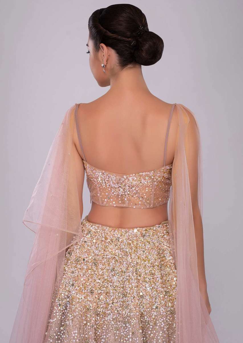 Dusty pink lehenga paired with multi paneled corset blouse  with attached net drape