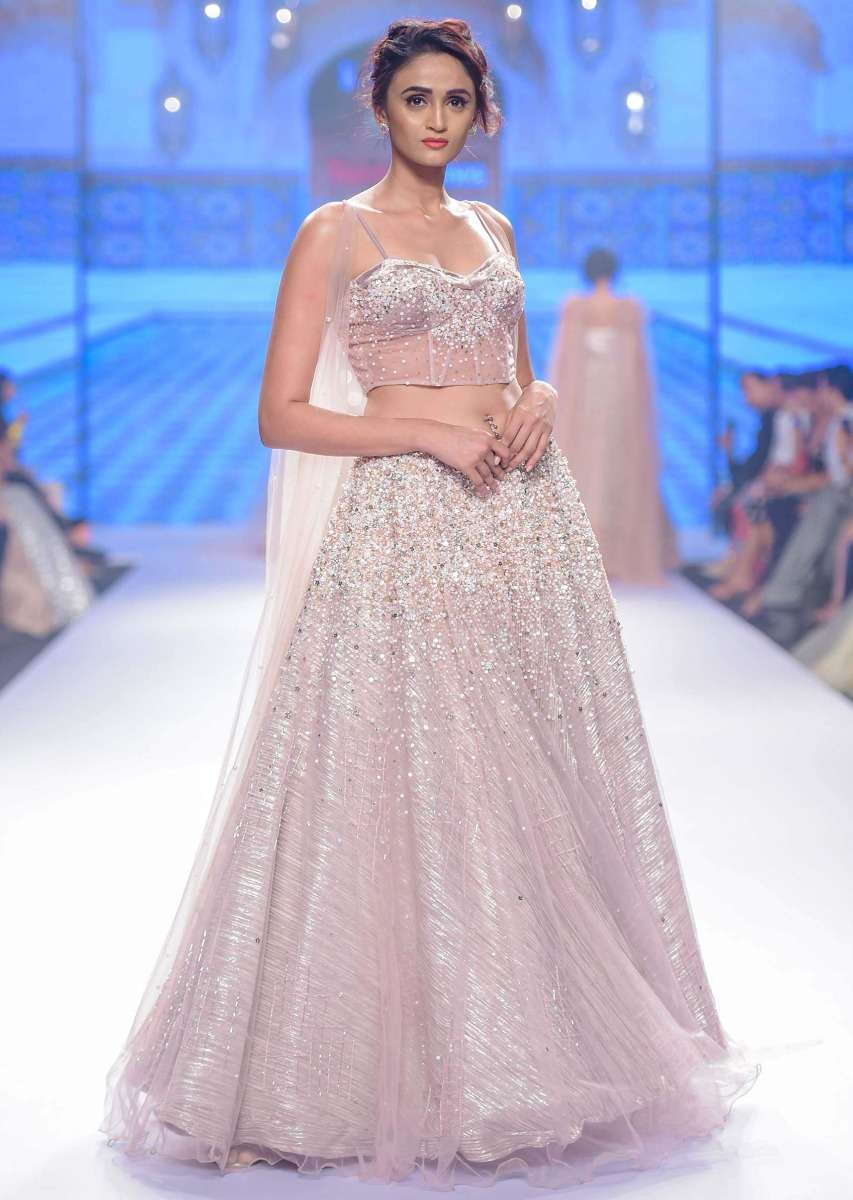 Dusty pink lehenga paired with multi paneled corset blouse  with attached net drape