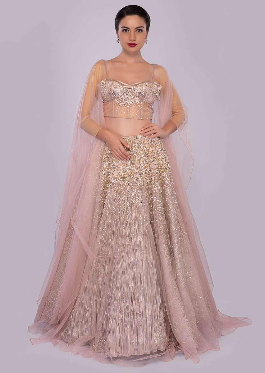 Dusty pink lehenga paired with multi paneled corset blouse  with attached net drape
