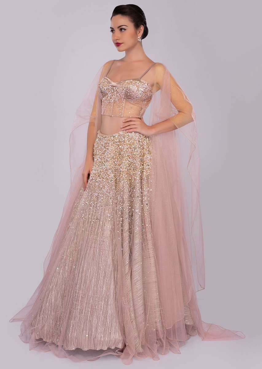Dusty pink lehenga paired with multi paneled corset blouse  with attached net drape