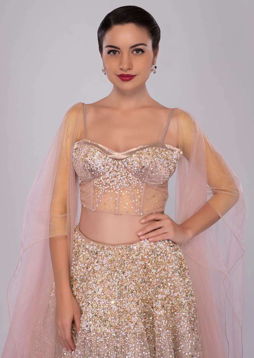 Dusty pink lehenga paired with multi paneled corset blouse  with attached net drape