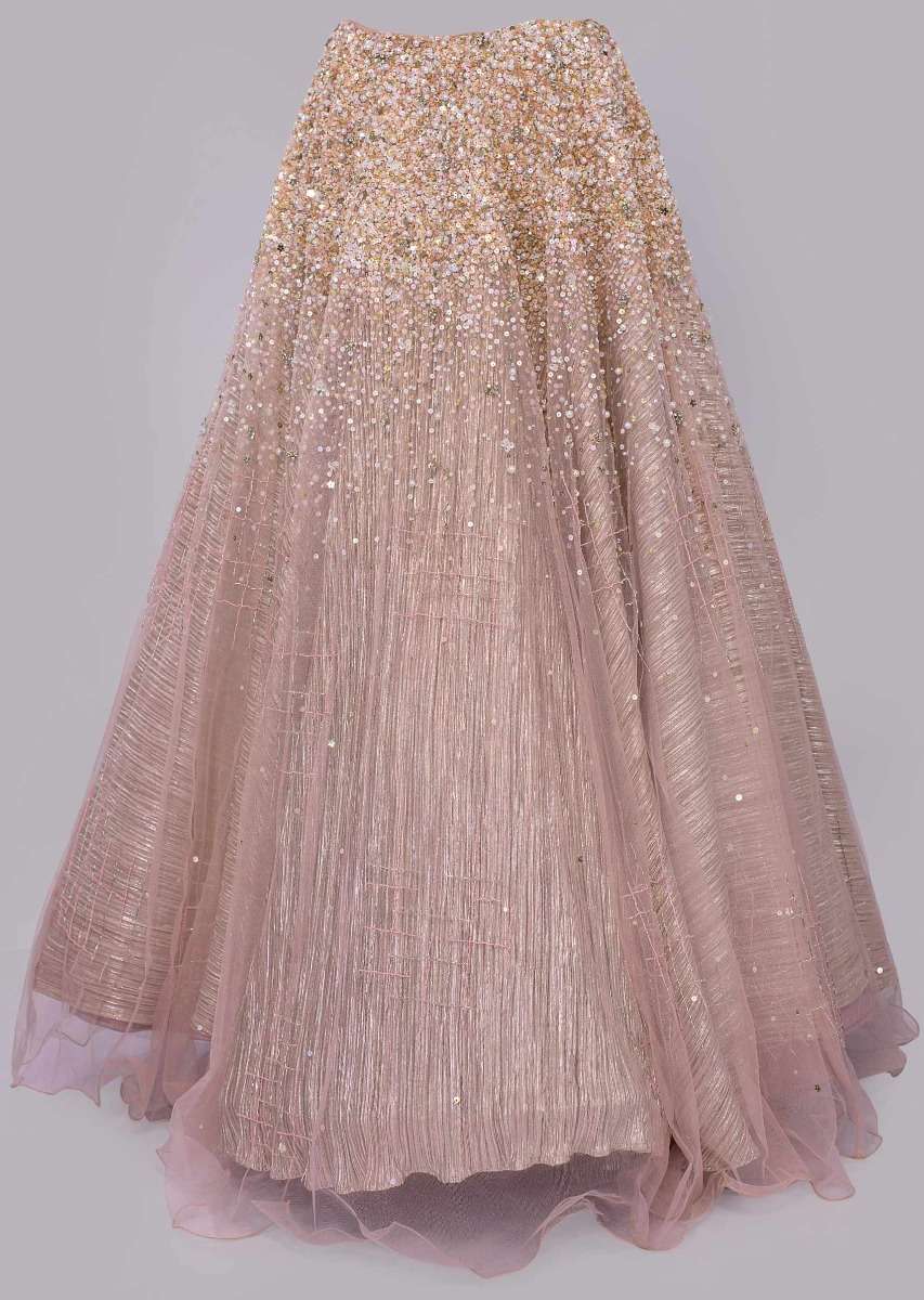 Dusty pink lehenga paired with multi paneled corset blouse  with attached net drape