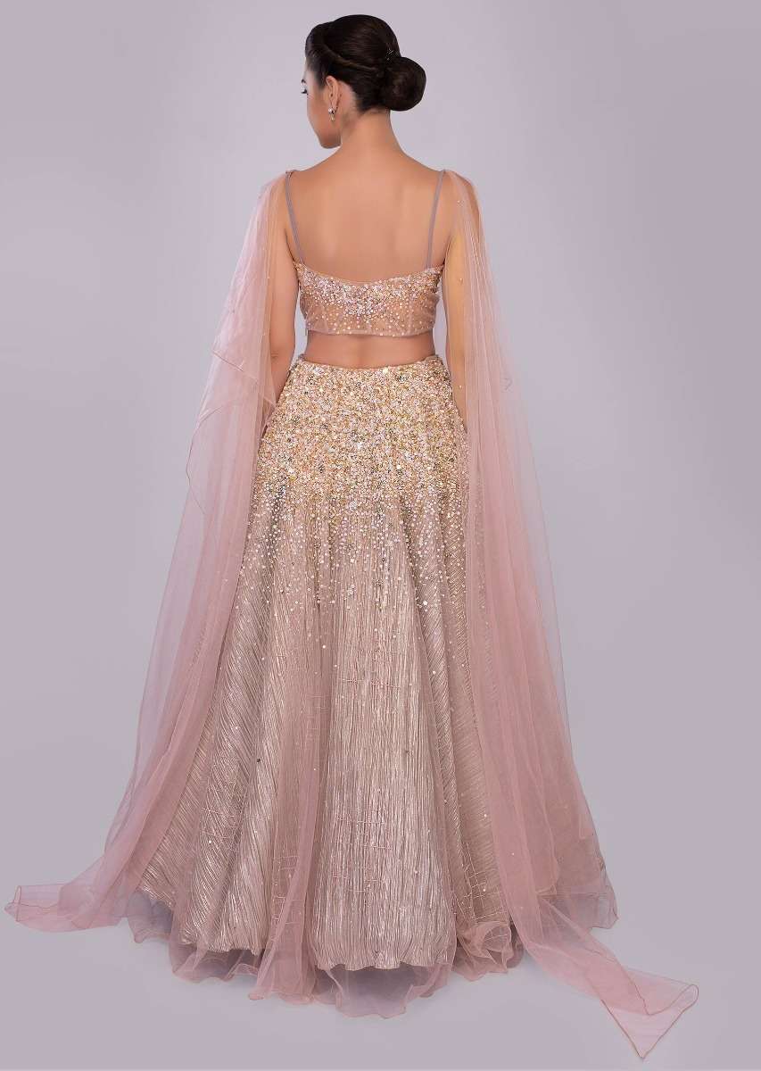 Dusty pink lehenga paired with multi paneled corset blouse  with attached net drape